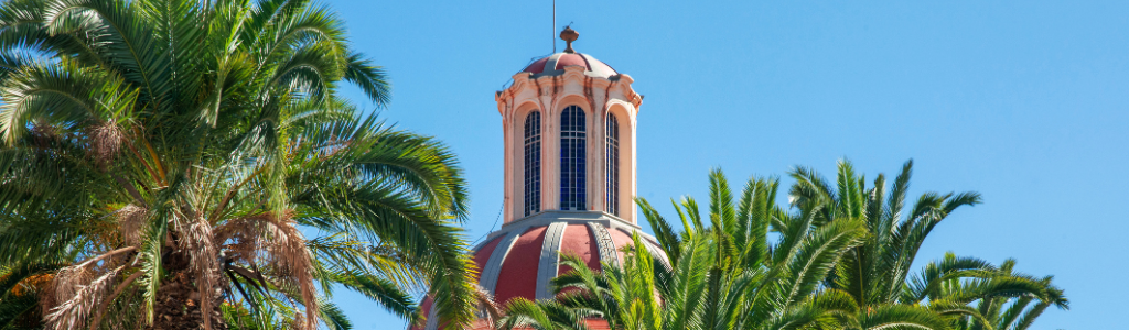 a picture showing the top of a building in colonial style Puerto de la Cruz, bright blue sky's and palm trees